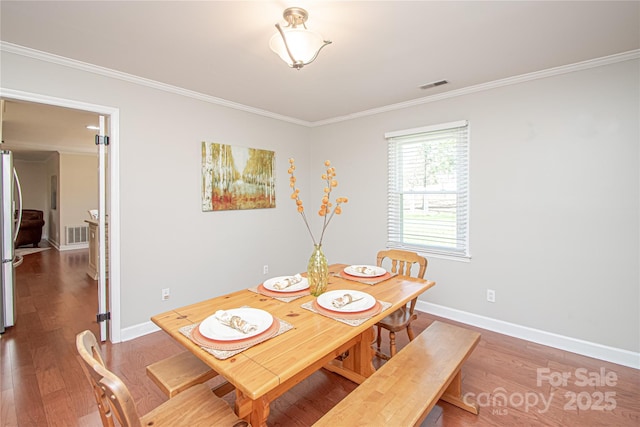 dining area with visible vents, crown molding, and wood finished floors