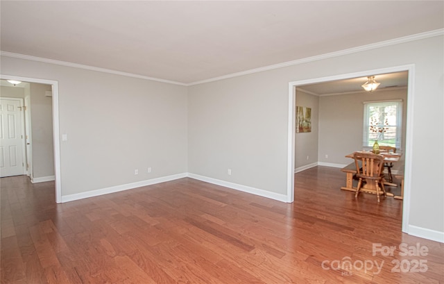 empty room featuring baseboards, wood finished floors, and crown molding