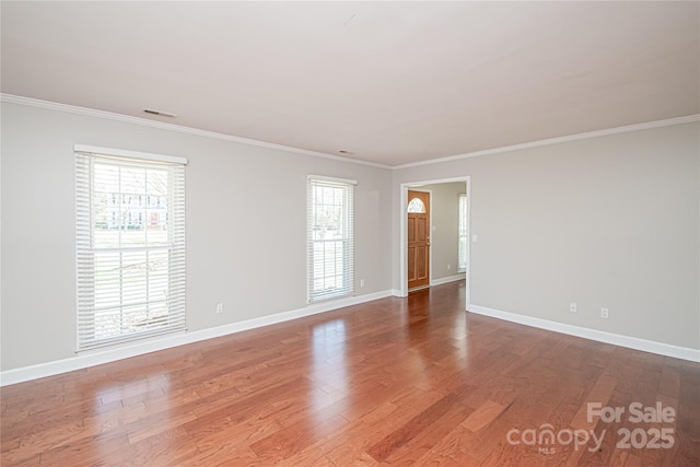 empty room with visible vents, crown molding, and wood finished floors