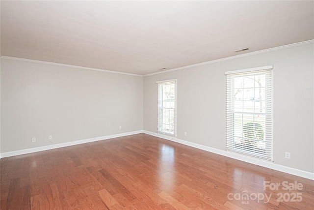 spare room featuring visible vents, ornamental molding, baseboards, and wood finished floors