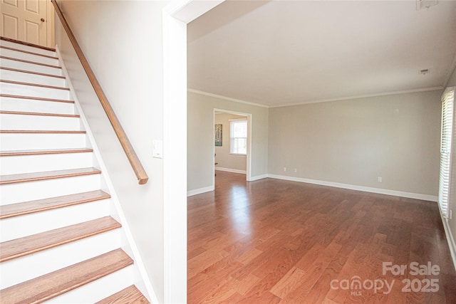 stairway featuring crown molding, wood finished floors, and baseboards