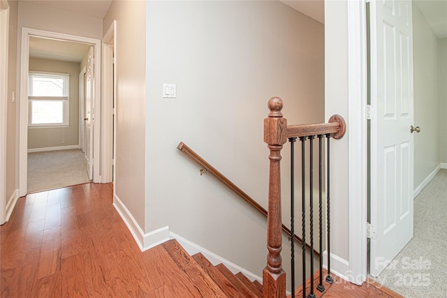 hallway featuring baseboards, an upstairs landing, and wood finished floors