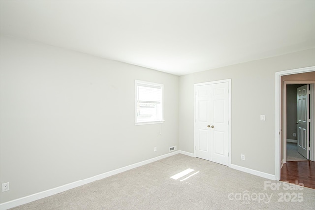 unfurnished bedroom featuring visible vents, carpet flooring, baseboards, and a closet