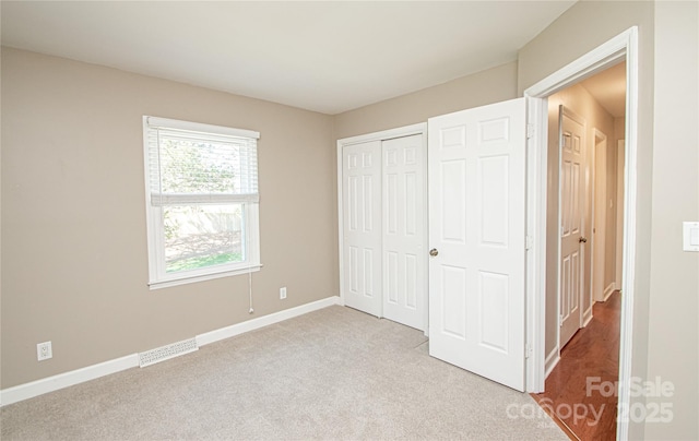 unfurnished bedroom with light colored carpet, baseboards, visible vents, and a closet