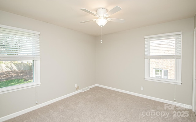 empty room featuring baseboards, light carpet, visible vents, and a ceiling fan