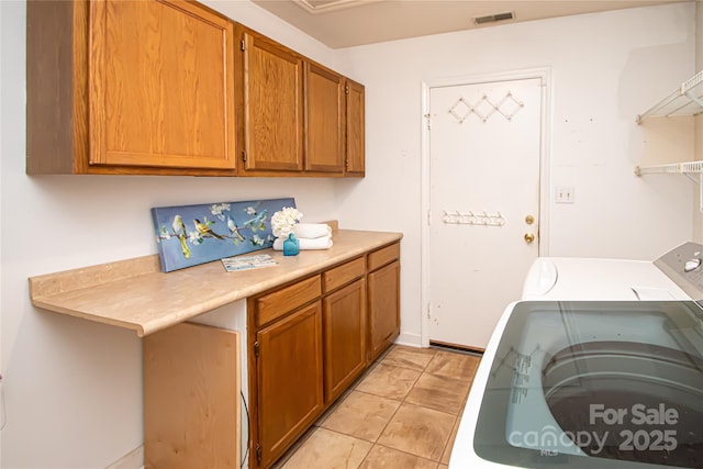 washroom with light tile patterned flooring, visible vents, cabinet space, and washer / clothes dryer