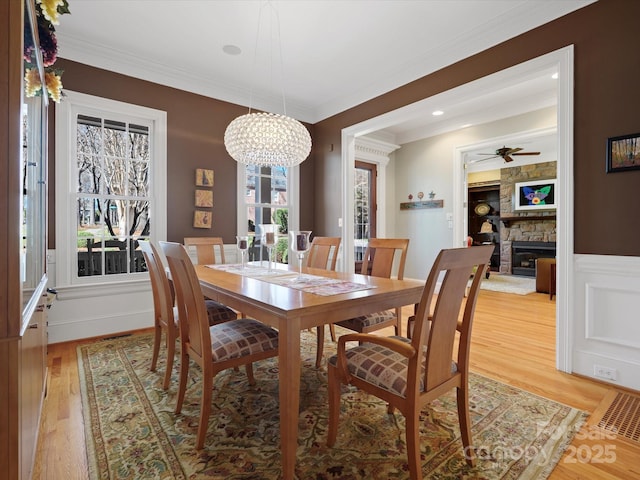 dining room with light wood-style flooring, ornamental molding, and a fireplace