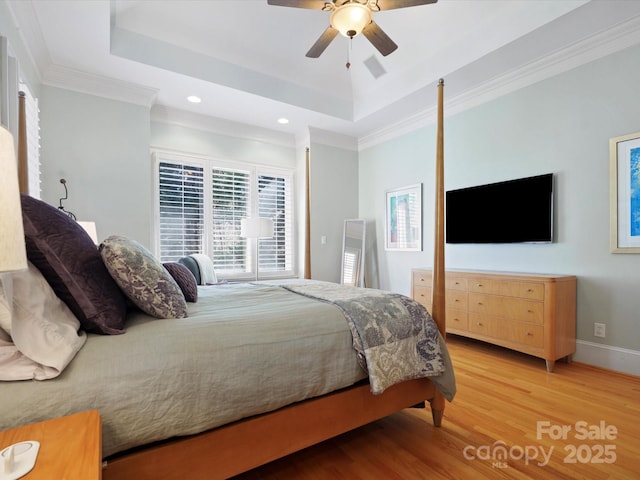 bedroom featuring wood finished floors, baseboards, a tray ceiling, recessed lighting, and ornamental molding