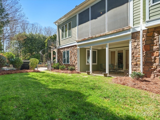 back of property featuring stone siding, stairs, a yard, and fence