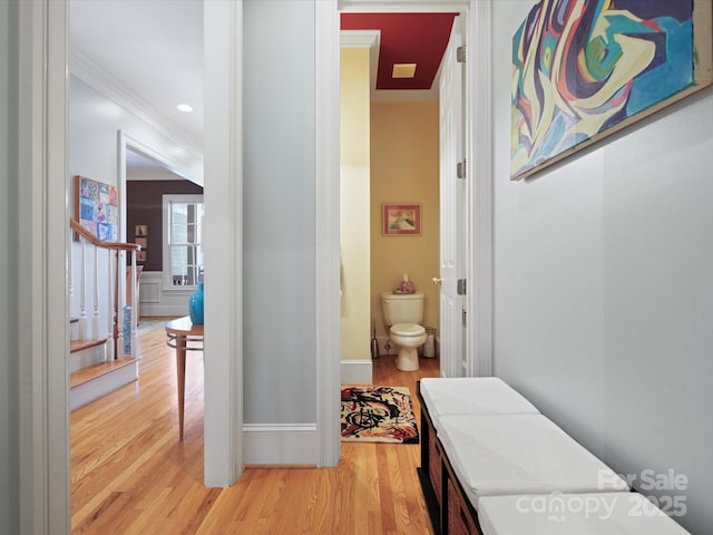 corridor with light wood-style flooring and ornamental molding