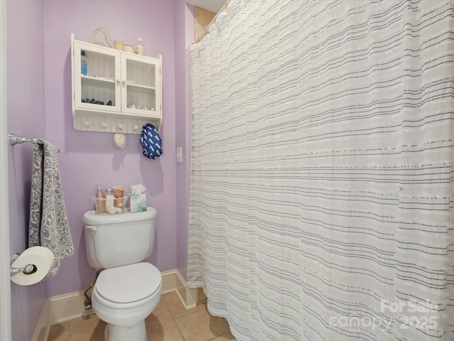 bathroom featuring tile patterned flooring, toilet, and baseboards