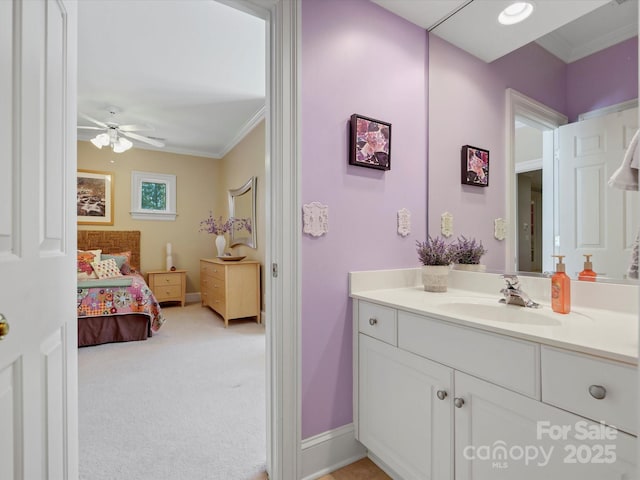 ensuite bathroom with ornamental molding, connected bathroom, baseboards, ceiling fan, and vanity