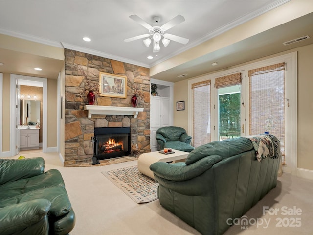 carpeted living area with visible vents, ornamental molding, a stone fireplace, baseboards, and ceiling fan