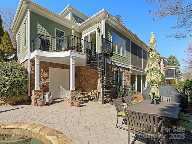 rear view of house with outdoor dining area, stone siding, a patio, and stairway