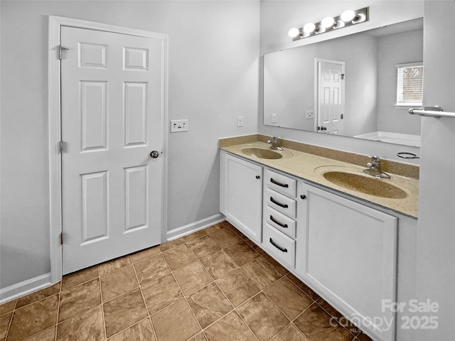 bathroom featuring double vanity, baseboards, tile patterned floors, and a sink