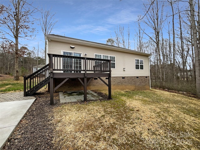 back of property with crawl space, a wooden deck, and a patio area