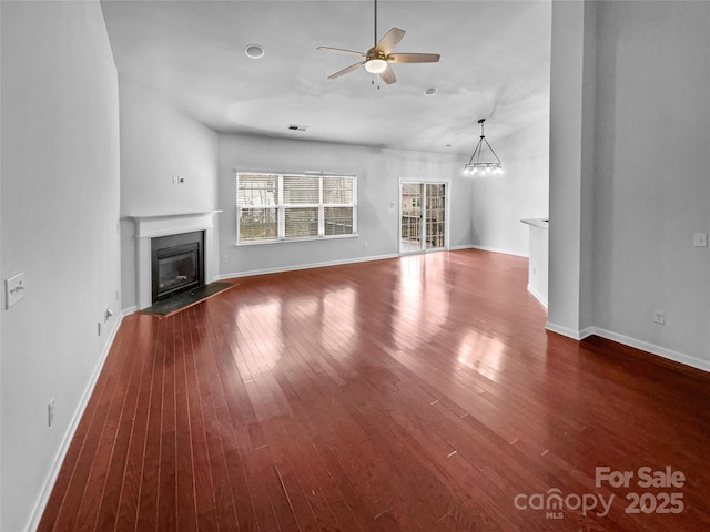 unfurnished living room featuring baseboards, wood-type flooring, a glass covered fireplace, and ceiling fan with notable chandelier