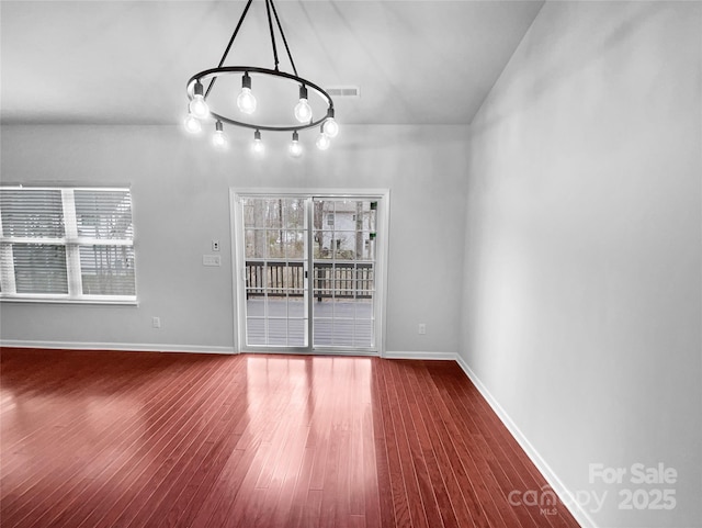 unfurnished dining area with visible vents, baseboards, a healthy amount of sunlight, and wood finished floors