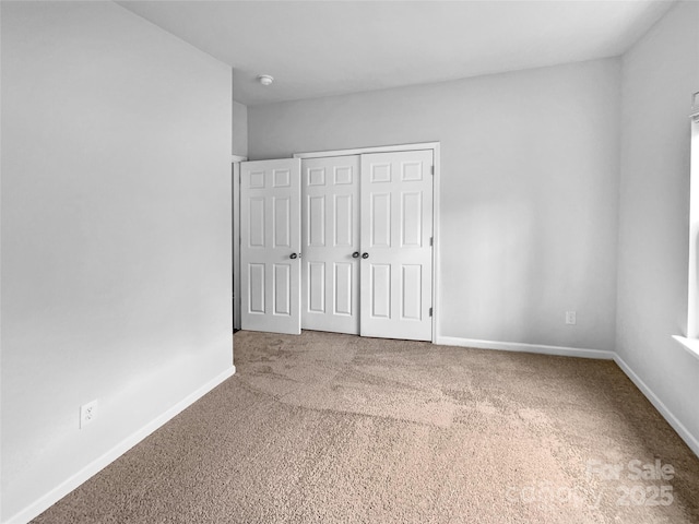 unfurnished bedroom featuring a closet, baseboards, and carpet floors