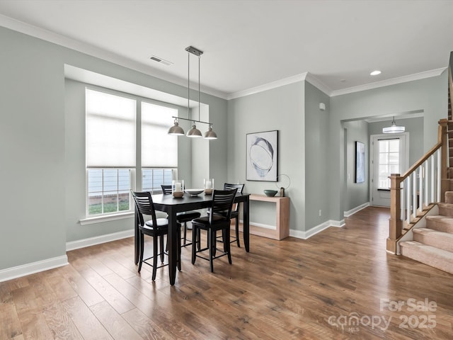 dining room featuring wood finished floors, visible vents, baseboards, stairs, and crown molding