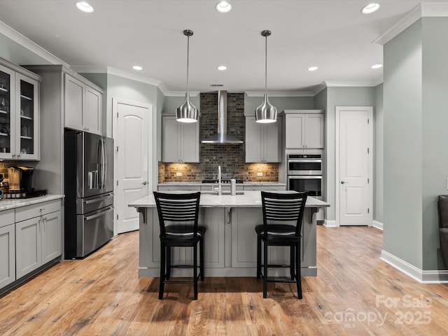 kitchen featuring baseboards, gray cabinets, appliances with stainless steel finishes, crown molding, and wall chimney range hood