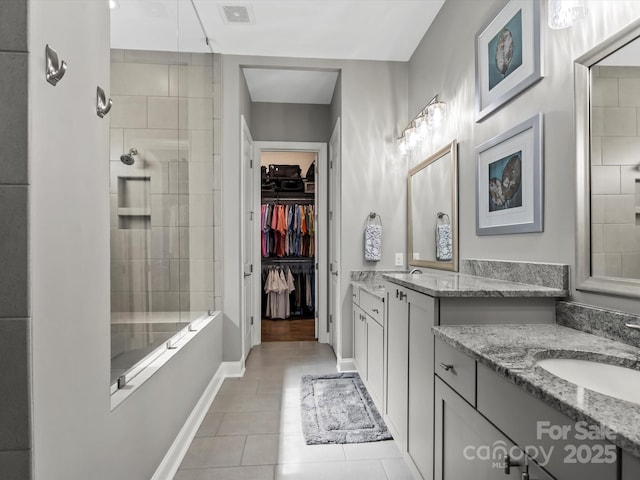 full bathroom featuring visible vents, baseboards, a tile shower, a sink, and tile patterned flooring