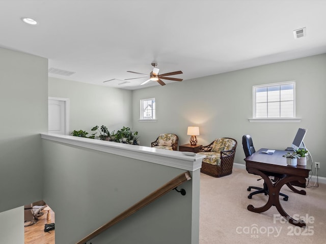 office area featuring baseboards, visible vents, and light carpet