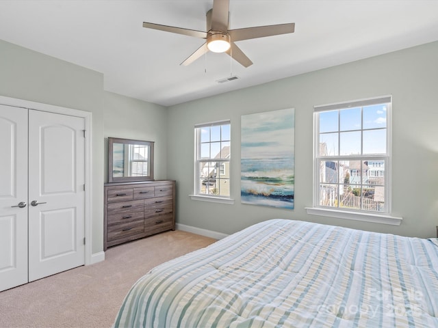 carpeted bedroom featuring baseboards, visible vents, a closet, and ceiling fan