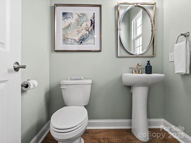 half bathroom featuring toilet, baseboards, and wood finished floors