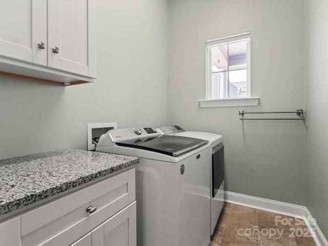 clothes washing area featuring cabinet space, washing machine and dryer, and baseboards