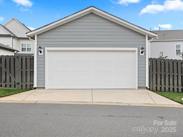 garage featuring driveway and fence