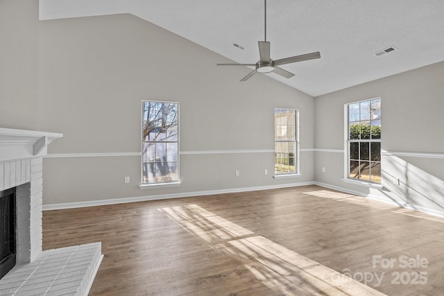 unfurnished living room with lofted ceiling, a brick fireplace, and wood finished floors