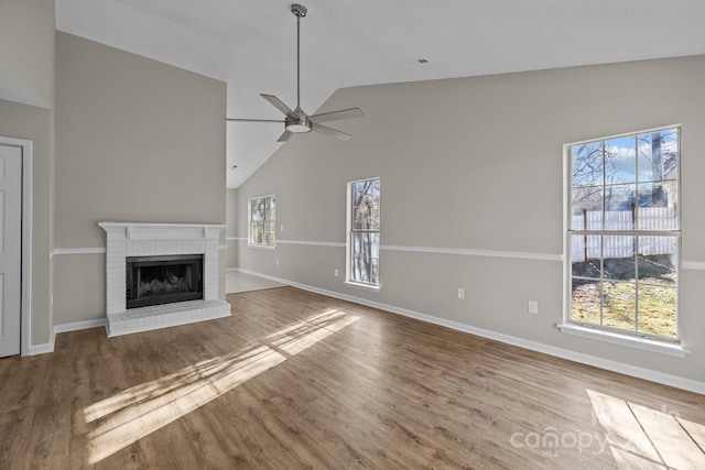 unfurnished living room featuring a brick fireplace, baseboards, a ceiling fan, and wood finished floors