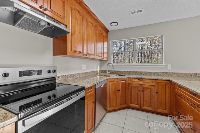 kitchen featuring brown cabinetry, visible vents, a sink, stainless steel appliances, and under cabinet range hood