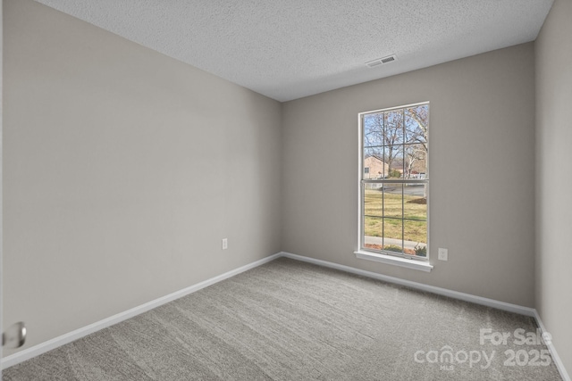 carpeted empty room with visible vents, baseboards, and a textured ceiling