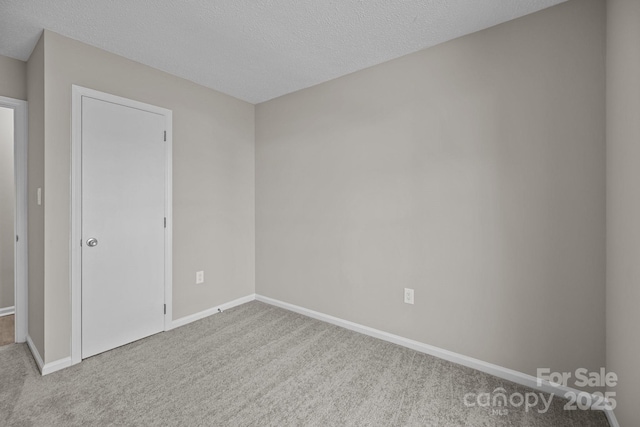 unfurnished bedroom with carpet flooring, a textured ceiling, and baseboards