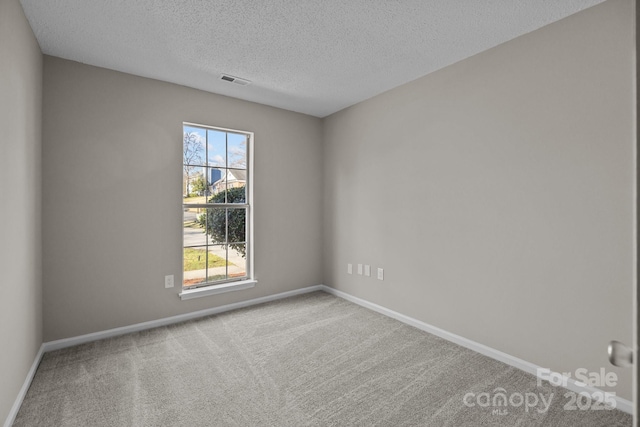 empty room with visible vents, baseboards, carpet, and a textured ceiling