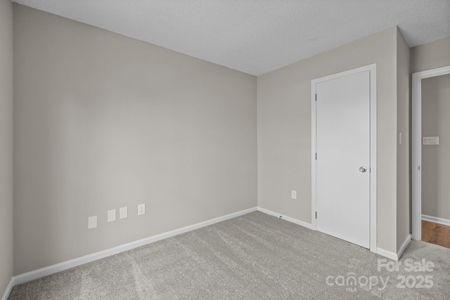 unfurnished bedroom featuring a textured ceiling, baseboards, and carpet