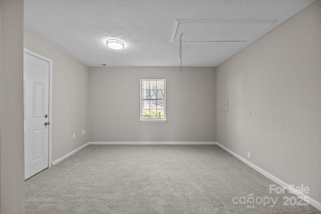 carpeted empty room with baseboards, a textured ceiling, and attic access