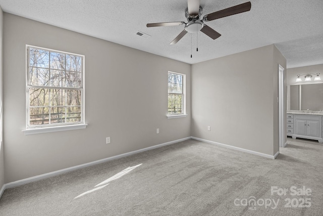 unfurnished bedroom featuring visible vents, carpet floors, baseboards, and ensuite bathroom