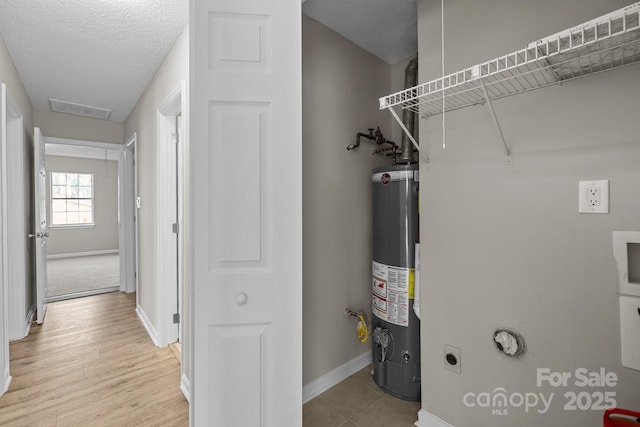 utility room with visible vents and water heater