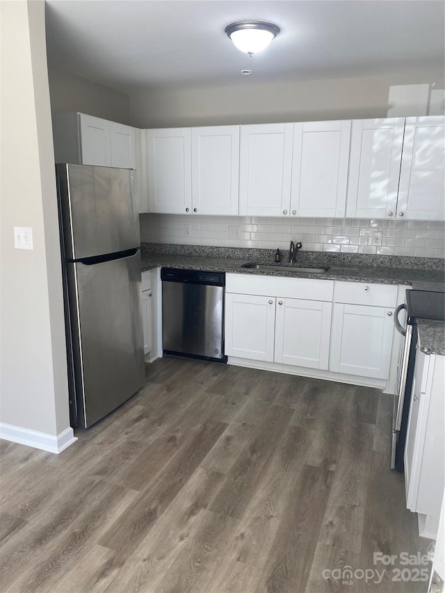 kitchen with a sink, appliances with stainless steel finishes, dark wood-style floors, and white cabinets