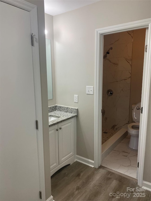 full bathroom featuring toilet, marble finish floor, a stall shower, baseboards, and vanity