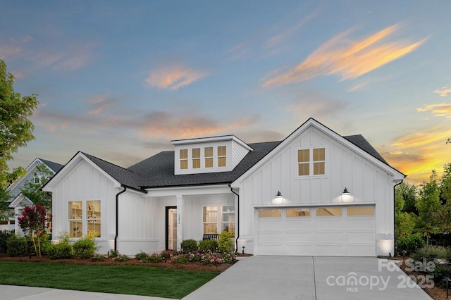 modern farmhouse with concrete driveway, board and batten siding, a front yard, and a shingled roof