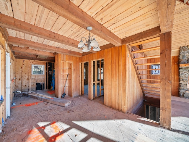 spare room featuring beamed ceiling, an inviting chandelier, and stairs