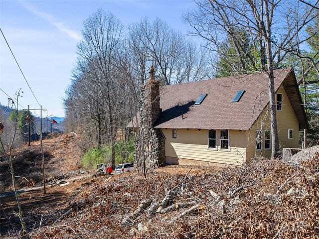 view of property exterior with a chimney and a shingled roof