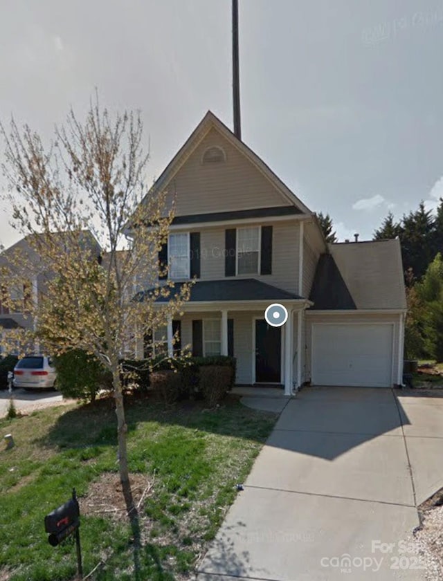 traditional-style house featuring a front lawn, an attached garage, and driveway