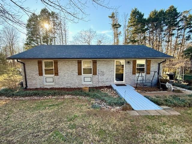 single story home featuring a front lawn, brick siding, and a shingled roof