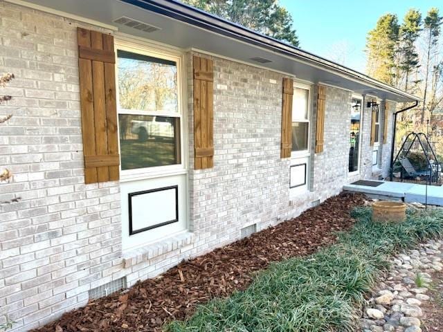 view of property exterior with crawl space and brick siding