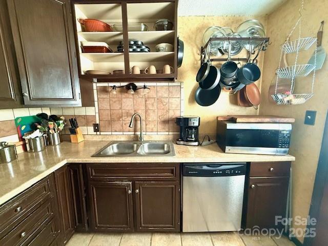 kitchen with dark brown cabinetry, light countertops, decorative backsplash, appliances with stainless steel finishes, and a sink